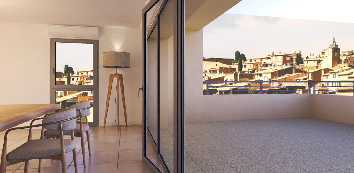 Séjour ouvert sur une grande terrasse dominant les toits d'un village provençal, clocher en arrière-plan.